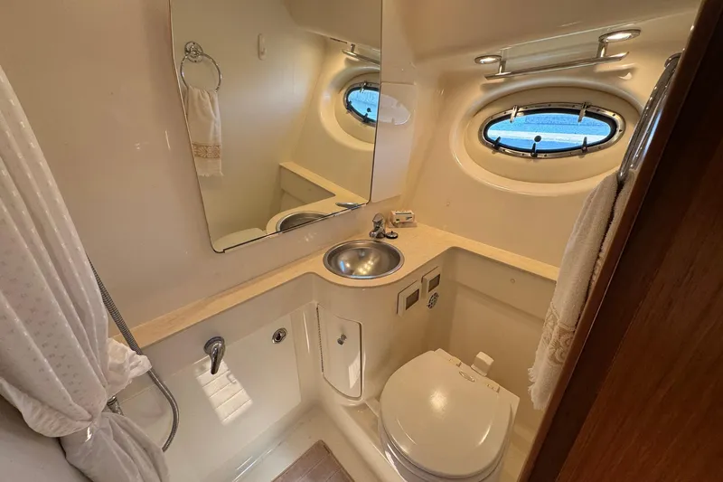 Lone Star Yacht Photos Pics Bathroom interior of 2005 Tiara Yachts 3200 Open, featuring sink, toilet, and porthole window.