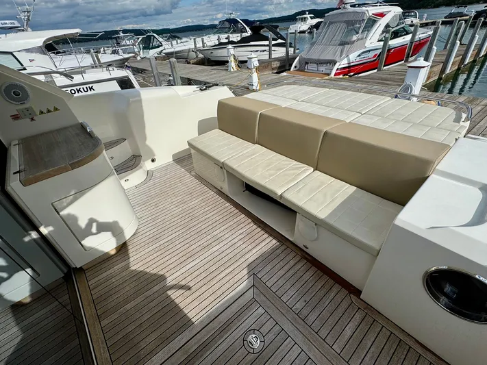 Yes Dear! Yacht Photos Pics 2016 Absolute Sport Yacht deck with beige seating and wooden flooring at a marina.