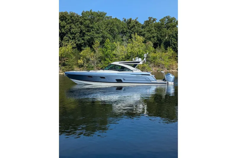  Yacht Photos Pics 2024 Formula 430 Super Sport Crossover boat on calm water, surrounded by lush greenery.