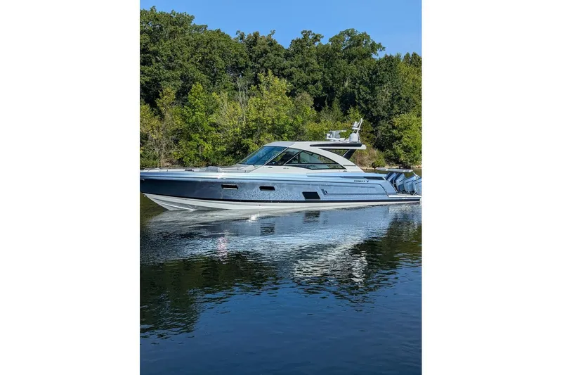  Yacht Photos Pics 2024 Formula 430 Super Sport Crossover yacht on calm water, surrounded by lush greenery.
