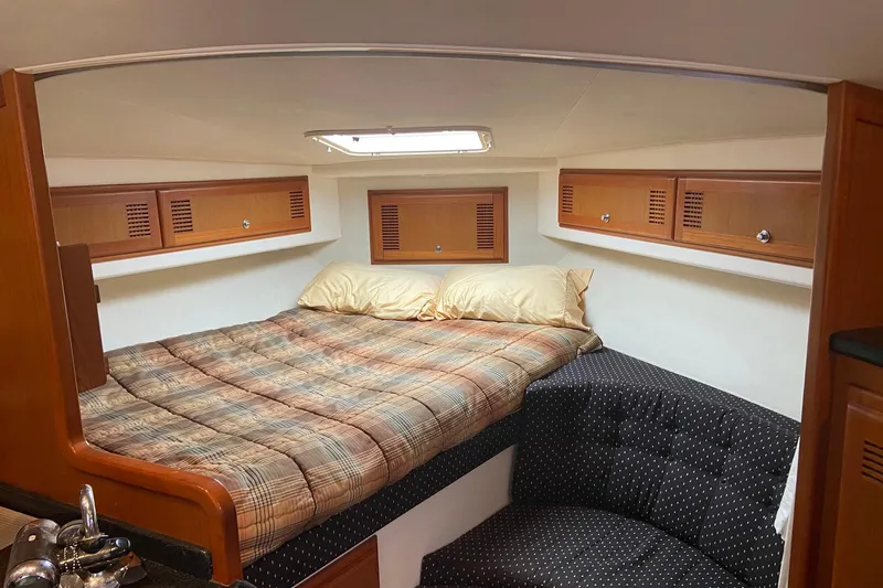 Dream Weaver Yacht Photos Pics 2002 Cabo 35 Express cabin interior with bed, wooden cabinets, and seating area.