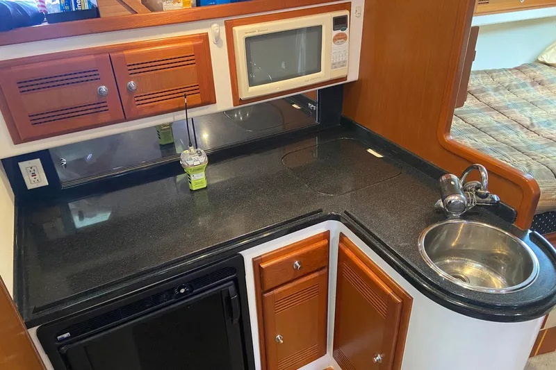 Dream Weaver Yacht Photos Pics 2002 Cabo 35 Express boat kitchen with sink, microwave, and wooden cabinets.