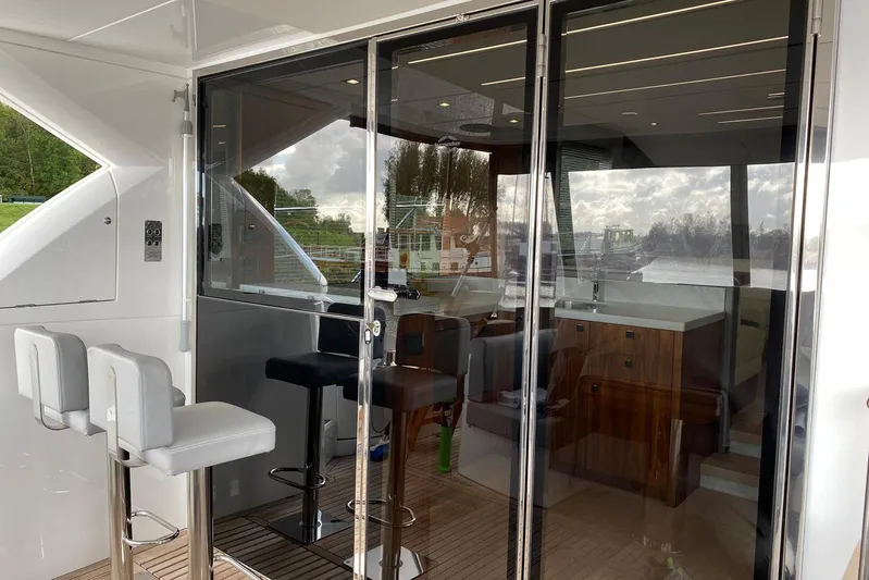  Yacht Photos Pics 2017 Sunseeker Manhattan 52 yacht interior with bar stools and glass doors.