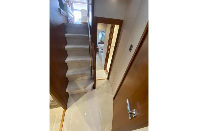  Yacht Photos Pics Interior staircase of 2017 Sunseeker Manhattan 52 yacht, featuring elegant wood and carpet design.