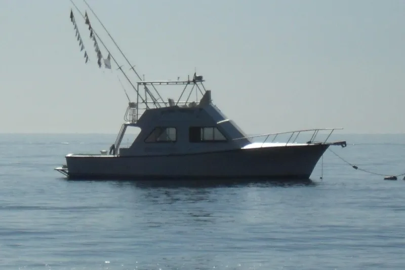 Pure Magic Yacht Photos Pics 2006 Island Hopper Sportfisher boat anchored on calm sea with fishing flags.