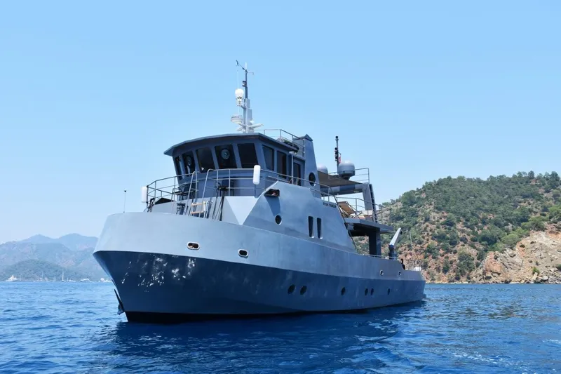 Risk Taker Yacht Photos Pics Tansu Custom Trawler 2006 on serene blue waters near a forested coastline.