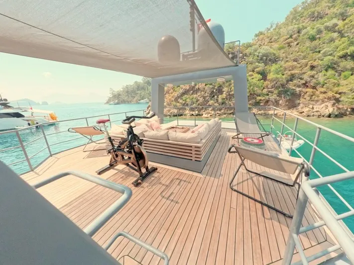 Risk Taker Yacht Photos Pics Luxurious deck of 2006 Tansu Custom Trawler with exercise bike, lounge chairs, and scenic ocean view.