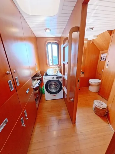 Risk Taker Yacht Photos Pics Laundry area and bathroom in 2006 Tansu Custom Trawler, featuring wood paneling and modern appliances.