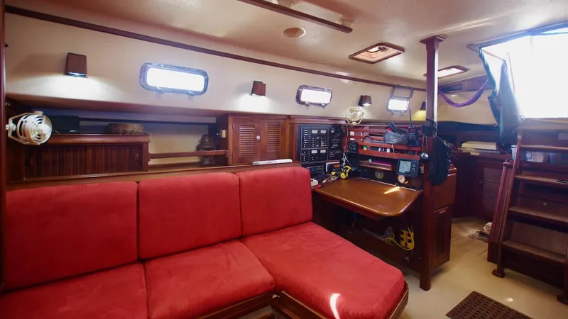 Azafran Yacht Photos Pics 1994 Island Packet 40 yacht interior with red seating, navigation station, and wooden cabinetry.