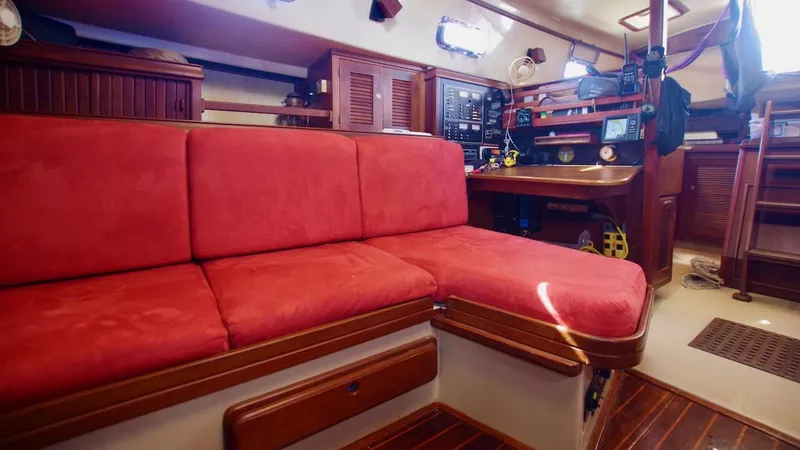 Azafran Yacht Photos Pics Interior of 1994 Island Packet 40 sailboat with red cushioned seating and navigation station.