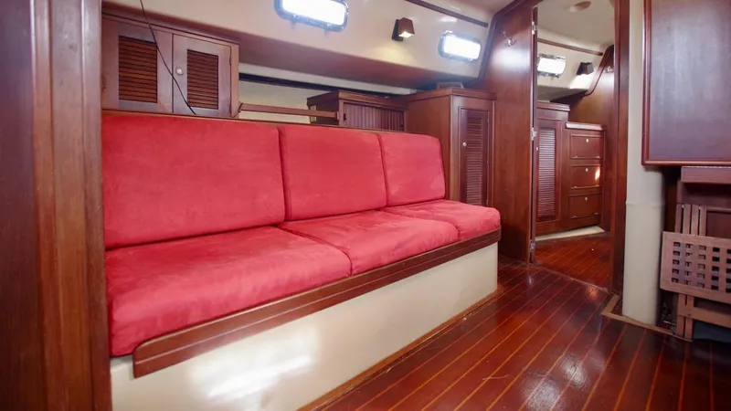 Azafran Yacht Photos Pics Interior of 1994 Island Packet 40 sailboat with red cushioned seating and wooden cabinetry.