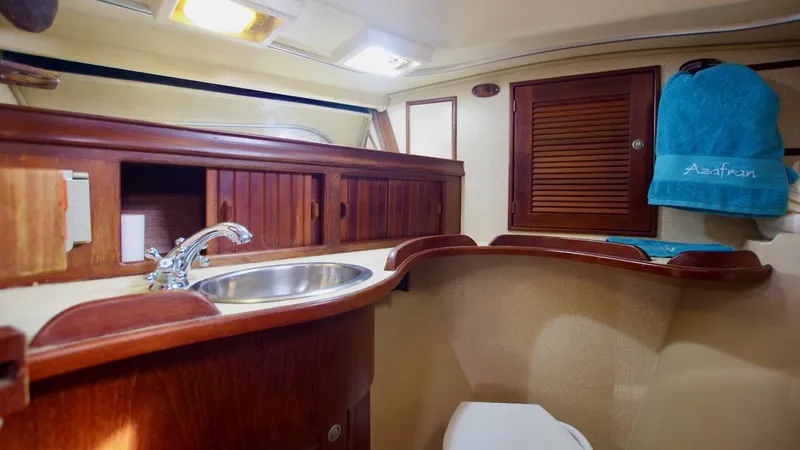 Azafran Yacht Photos Pics Interior of 1994 Island Packet 40 sailboat bathroom with wooden cabinetry and sink.