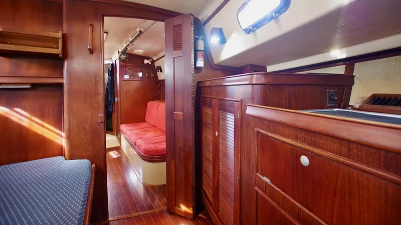 Azafran Yacht Photos Pics Interior of 1994 Island Packet 40 sailboat with wooden cabinetry and red seating.
