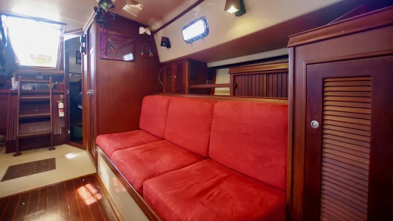 Azafran Yacht Photos Pics Interior of 1994 Island Packet 40 yacht with red cushioned seating and wooden cabinetry.