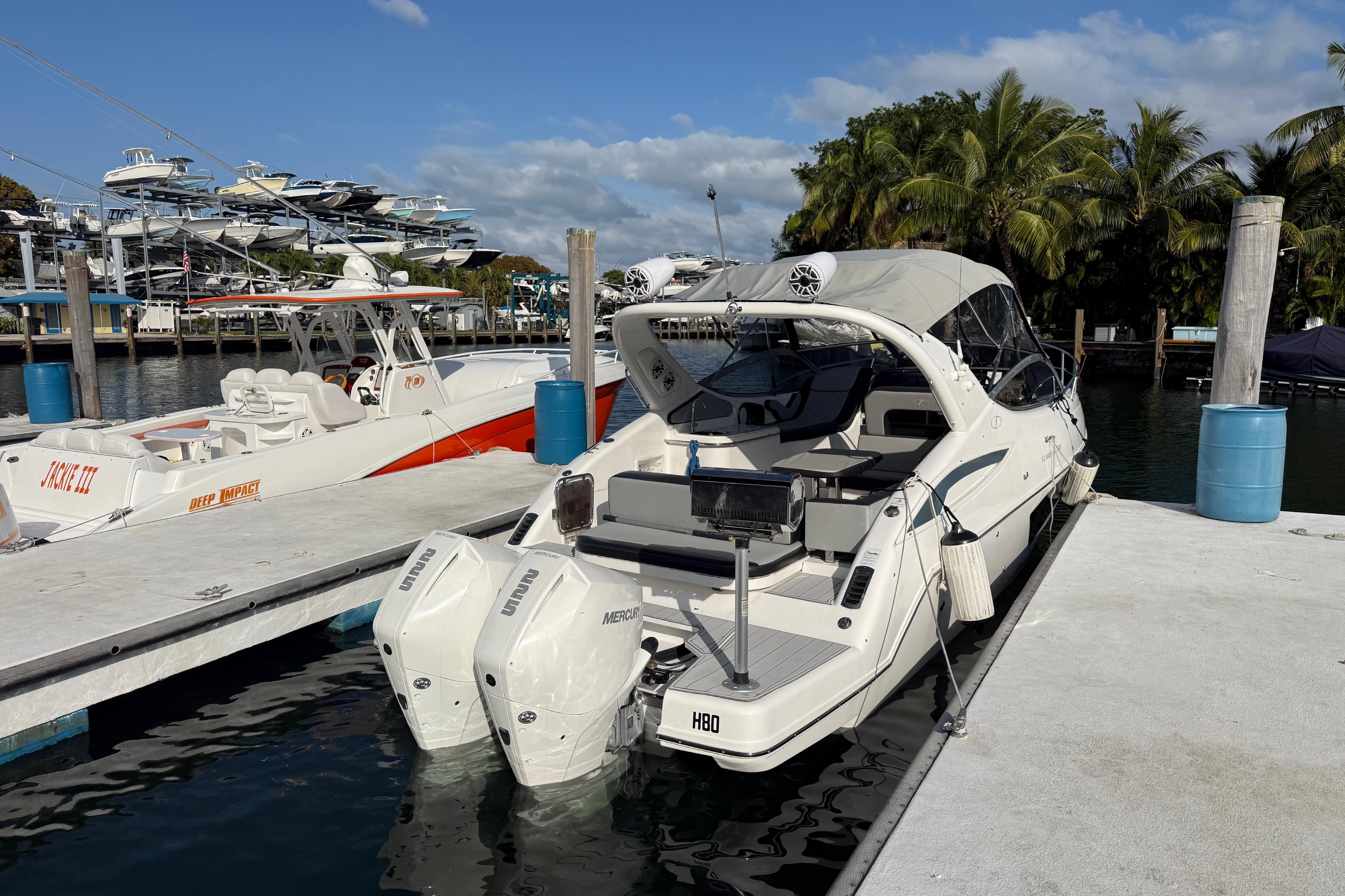 2021 Schaefer 303 boat docked at marina with palm trees and clear sky.