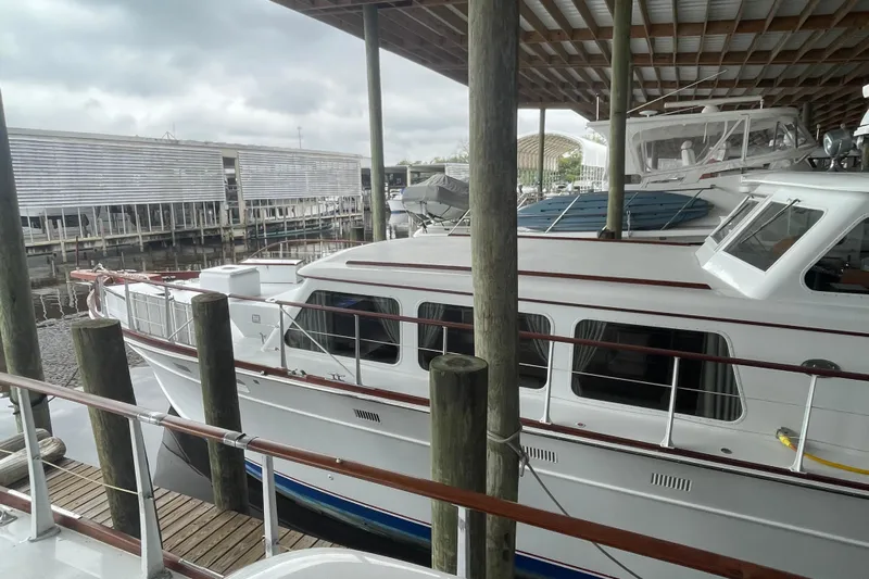 Georgia Yacht Photos Pics 1967 Huckins Offshore yacht docked under a covered marina with overcast skies.