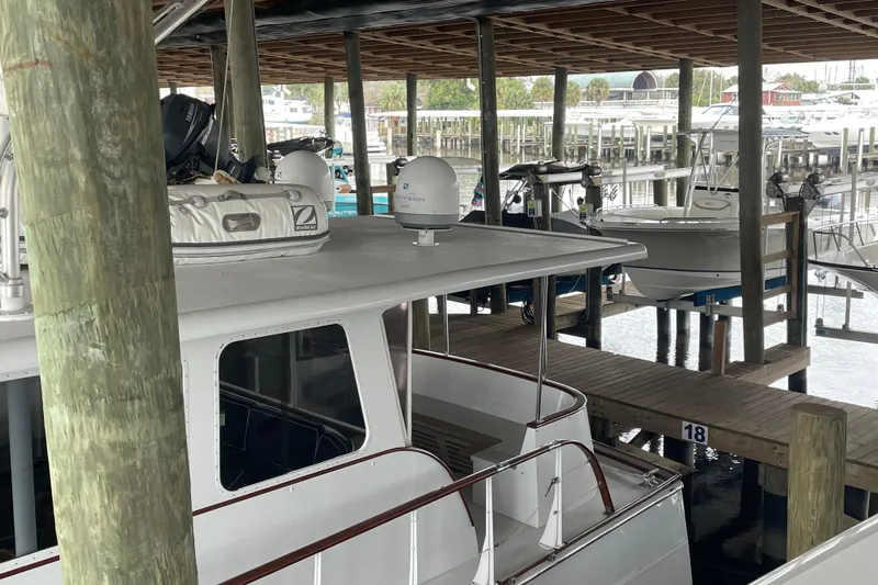 Georgia Yacht Photos Pics 1967 Huckins Offshore boat docked in a marina, under a wooden shelter.
