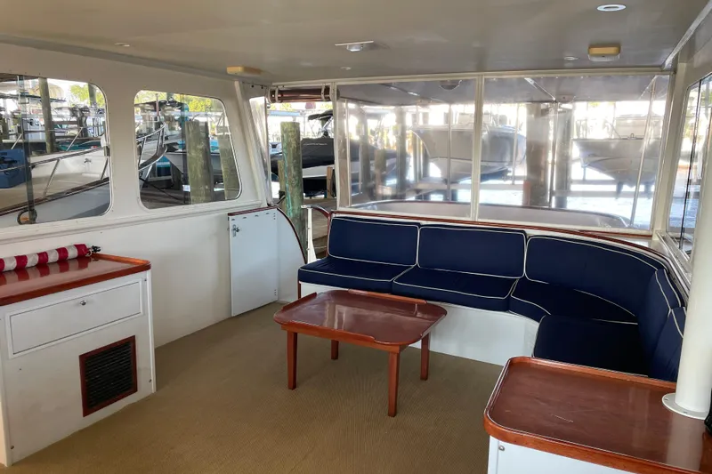 Georgia Yacht Photos Pics 1967 Huckins Offshore yacht interior with blue seating and wooden table, docked at marina.
