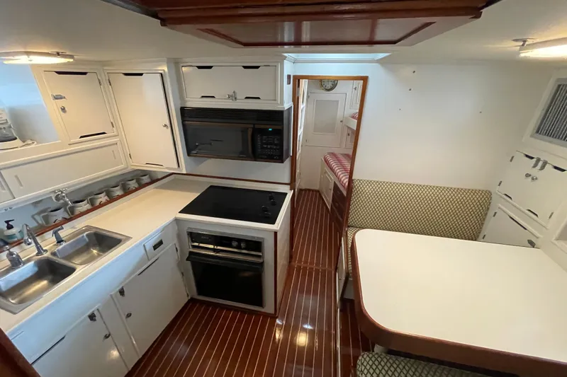 Georgia Yacht Photos Pics 1967 Huckins Offshore yacht interior with kitchen and dining area, featuring wood flooring.