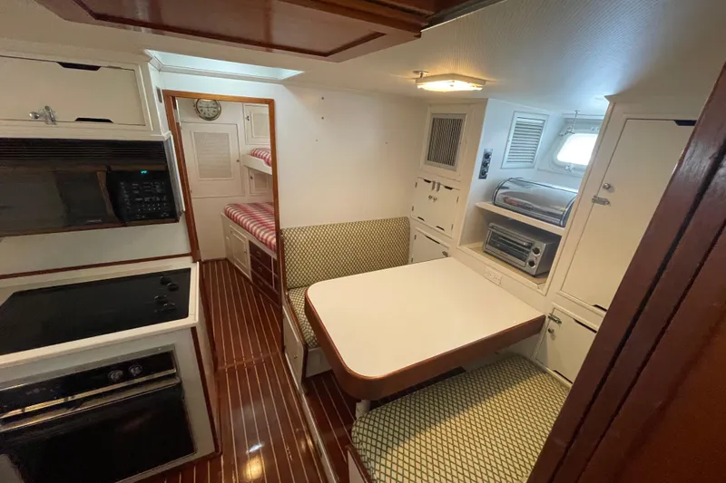 Georgia Yacht Photos Pics 1967 Huckins Offshore yacht interior with dining area, kitchenette, and bunk beds.