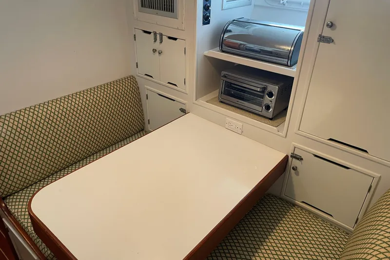 Georgia Yacht Photos Pics 1967 Huckins Offshore yacht interior with dining area, patterned seating, and compact kitchen appliances.