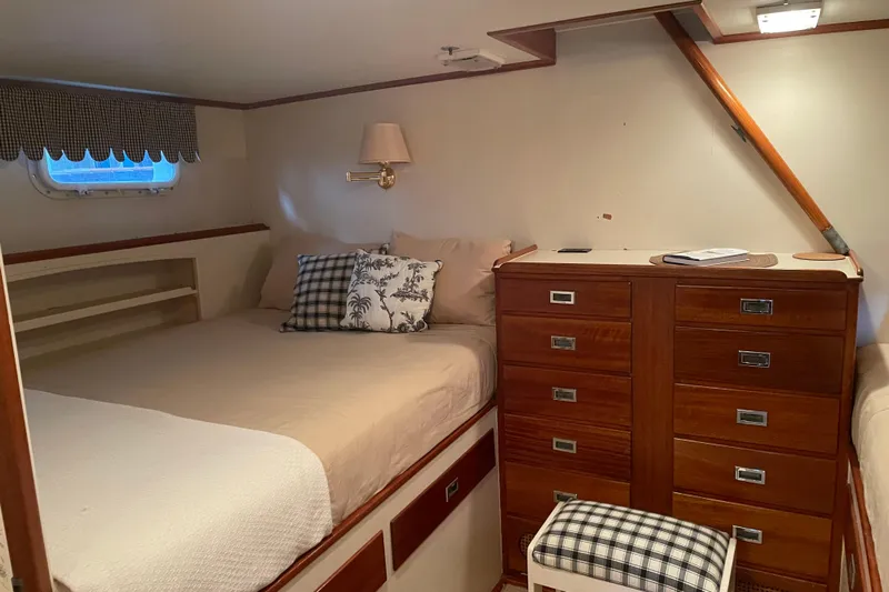 Georgia Yacht Photos Pics Cozy 1967 Huckins Offshore yacht cabin with bed, wooden drawers, and nautical decor.