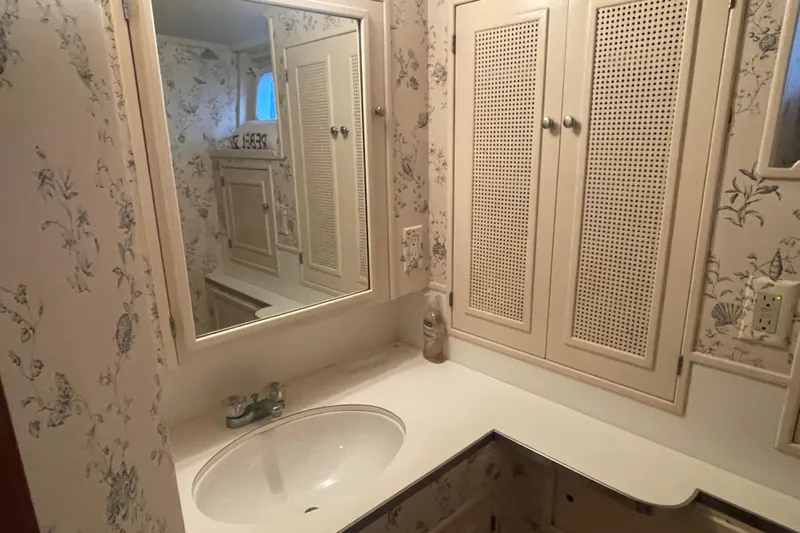 Georgia Yacht Photos Pics Vintage 1967 Huckins Offshore yacht bathroom with floral wallpaper and classic cabinetry.