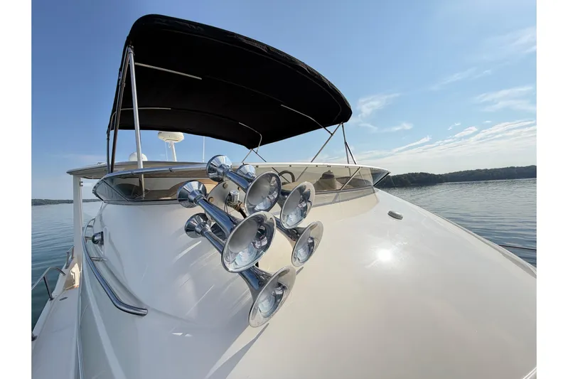 This Bar Yacht Photos Pics 2004 Meridian 459 Motoryacht with chrome horns, black canopy, and serene water backdrop.