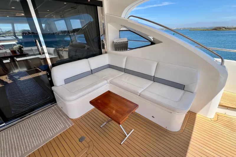  Yacht Photos Pics Luxurious 2010 Princess V78 yacht deck with white seating and wooden table, overlooking serene waters.