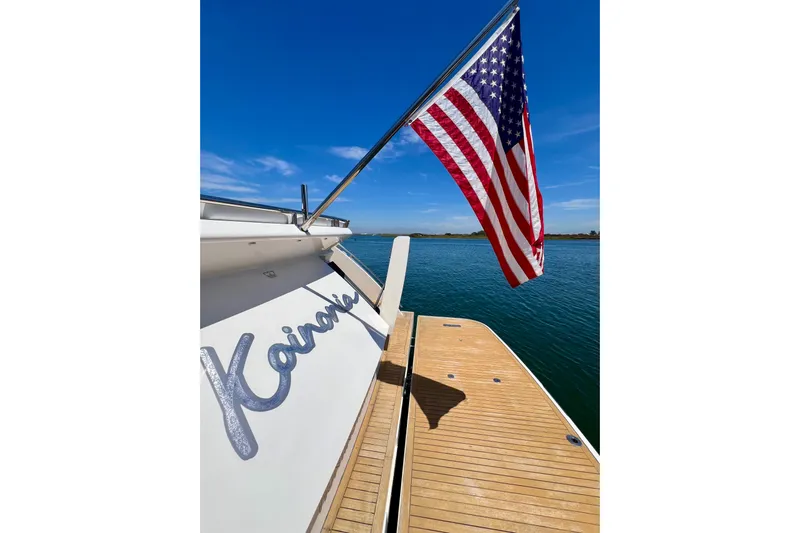  Yacht Photos Pics American flag on 2010 Princess V78 yacht, docked on calm water under clear blue sky.
