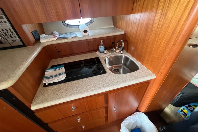  Yacht Photos Pics 2003 Tiara Yachts 3100 Open galley with sink, stove, and wooden cabinetry.