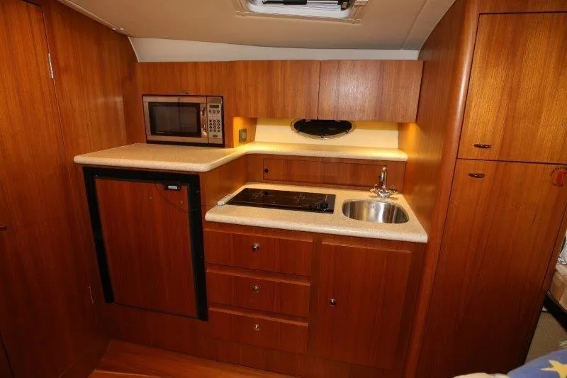  Yacht Photos Pics 2003 Tiara Yachts 3100 Open galley with wood cabinetry, sink, stove, and microwave.