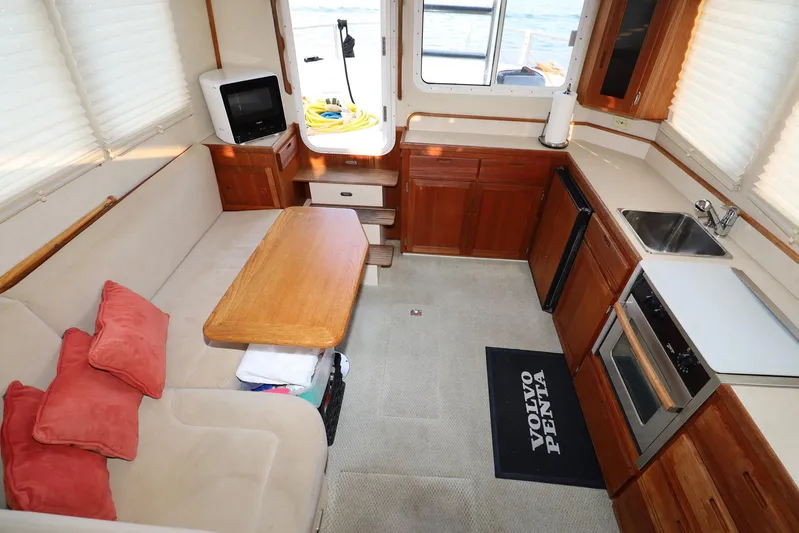 Edgin Yacht Photos Pics Interior of 2007 Nordic Tug 32, featuring cozy seating, kitchenette, and wooden cabinetry.