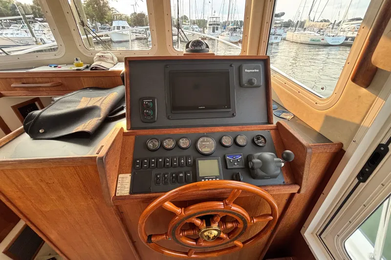 Edgin Yacht Photos Pics 2007 Nordic Tug 32 helm with wooden wheel, navigation instruments, and marina view.