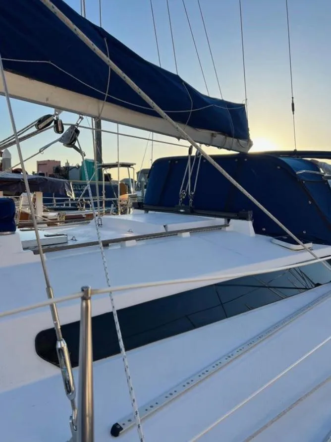 Sailing yacht Gib'Sea 126, 1985 model, with blue sails at sunset in a marina.