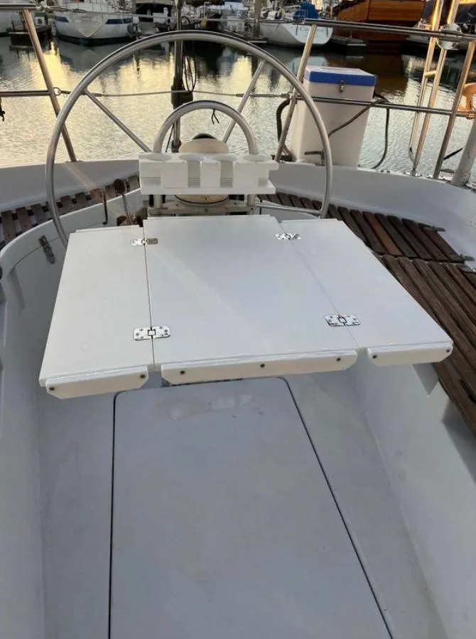 Cockpit of 1985 Gib'Sea 126 sailboat with steering wheel and foldable table.