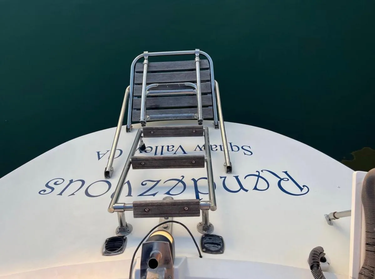 Gib'Sea 126 sailboat stern with ladder, 1985 model, docked in calm water.
