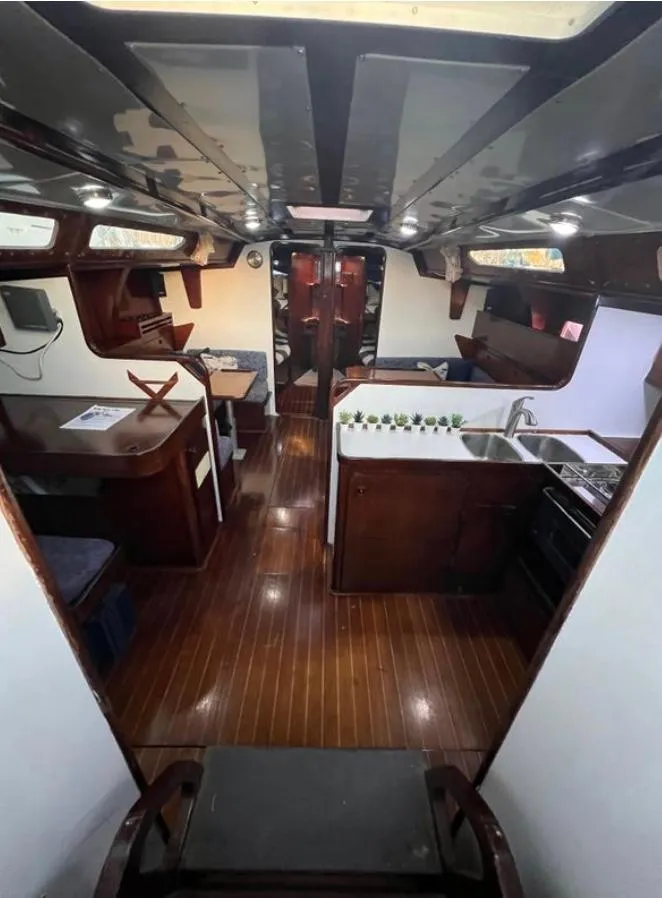 Interior of 1985 Gib'Sea 126 sailboat with wooden flooring and compact kitchen area.