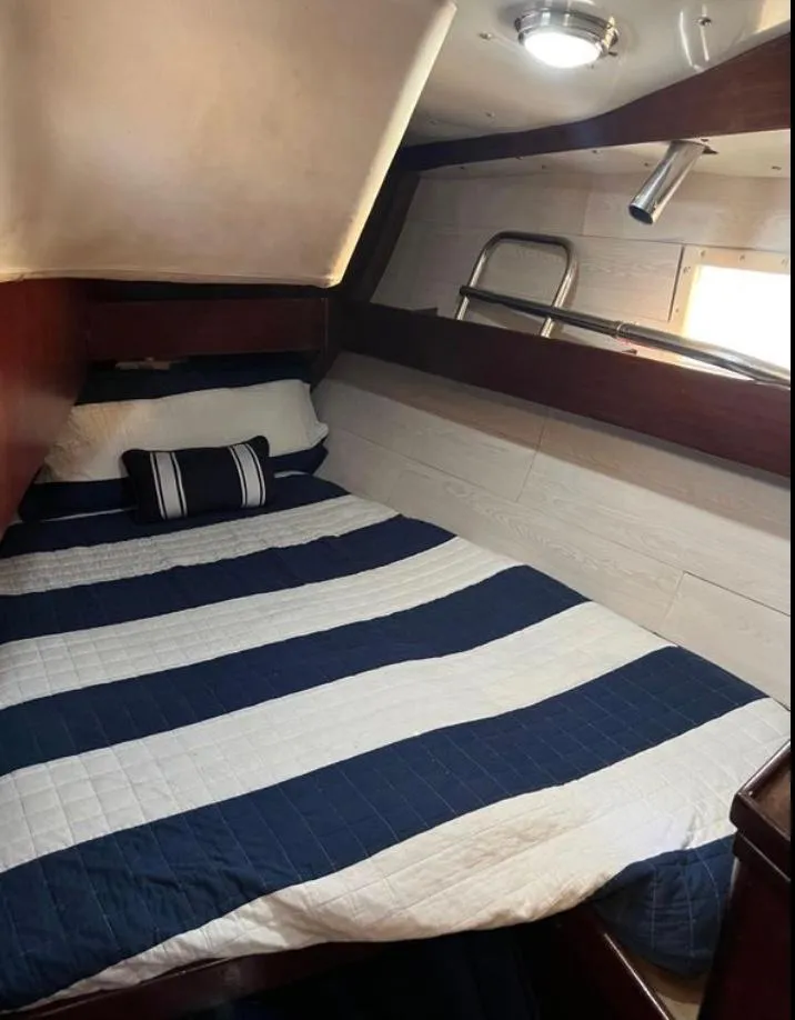 Cozy cabin interior of 1985 Gib'Sea 126 sailboat with striped bedding.