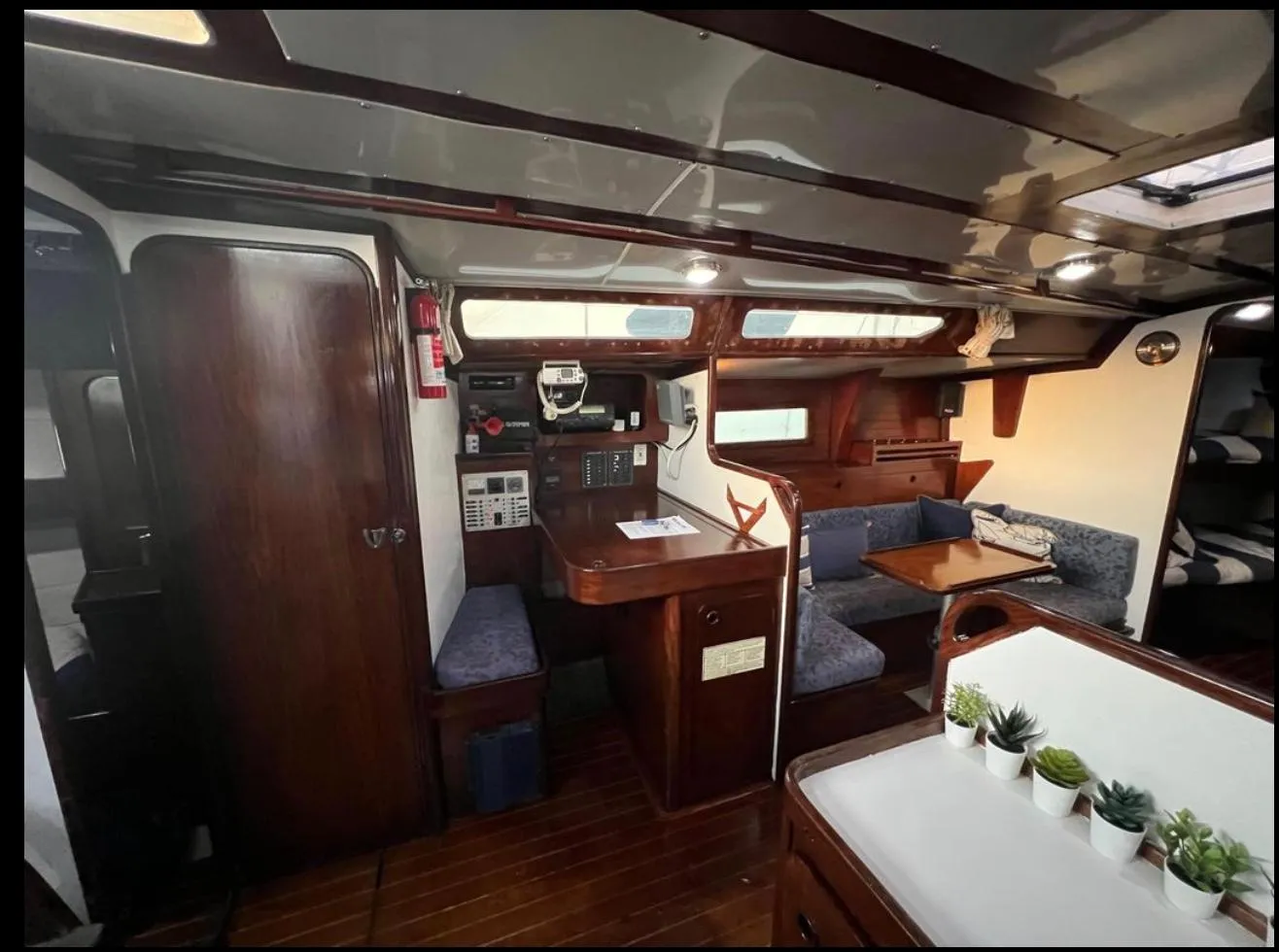 Interior of 1985 Gib'Sea 126 sailboat with wooden furnishings and cozy seating area.