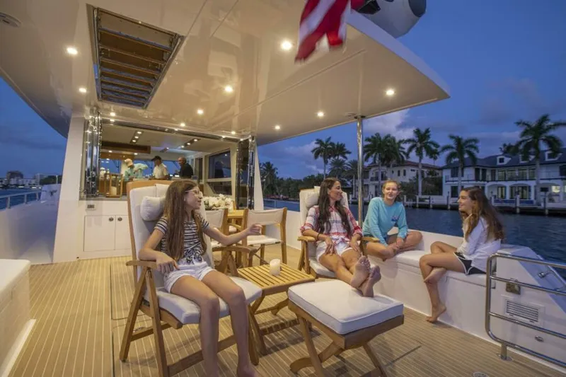  Yacht Photos Pics Group enjoying evening on 2026 Outback Yachts Outback 50, docked by waterfront homes.