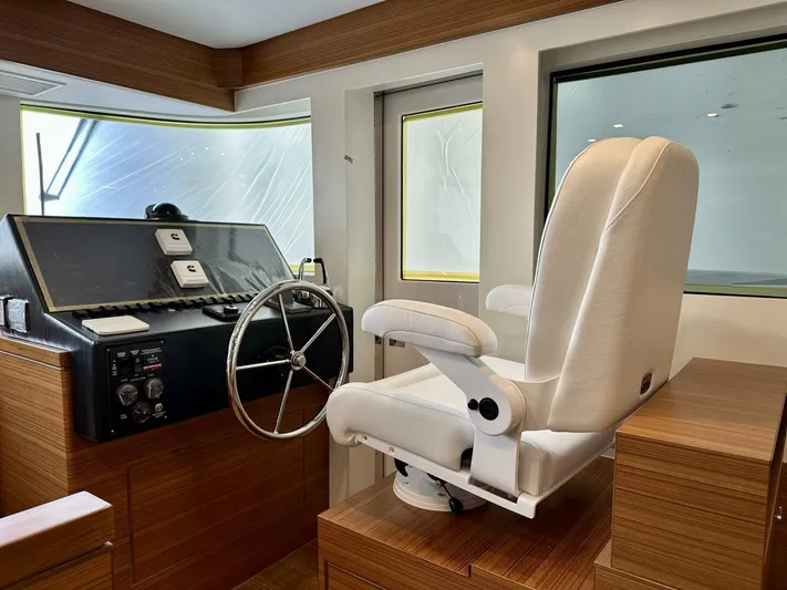  Yacht Photos Pics Helm station of 2026 Outback Yachts Outback 50 with white captain's chair and steering wheel.