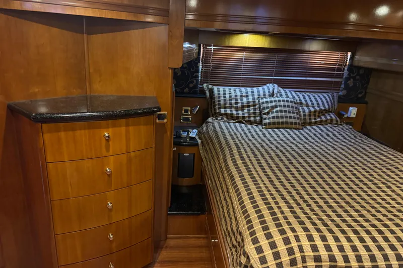 Size Matter's Yacht Photos Pics Luxurious 2001 Carver 530 Voyager Pilothouse bedroom with wood cabinetry and checkered bedding.