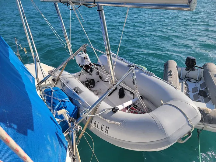 Cat Tales Yacht Photos Pics Inflatable dinghy on a 1996 Fountaine Pajot Tobago 35 catamaran, anchored in clear blue water.
