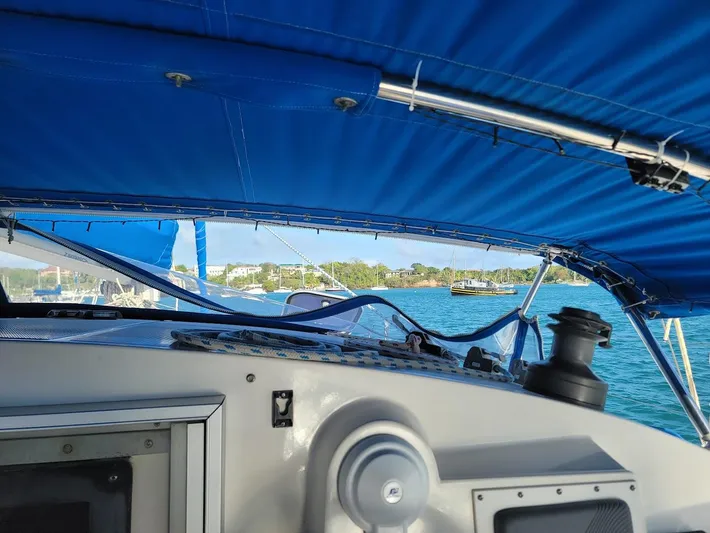Cat Tales Yacht Photos Pics 1996 Fountaine Pajot Tobago 35 sailboat cockpit with blue canopy, overlooking serene waters.