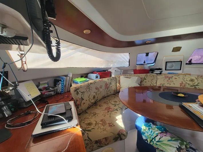 Cat Tales Yacht Photos Pics Interior of 1996 Fountaine Pajot Tobago 35 catamaran with floral seating and wooden table.