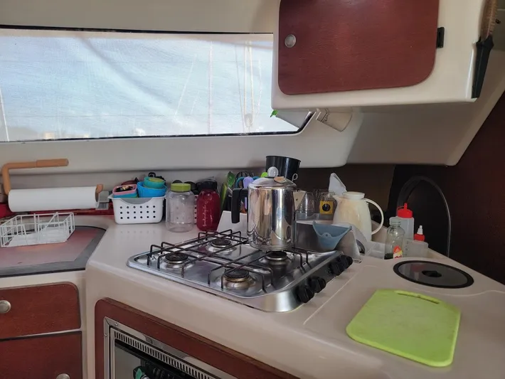 Cat Tales Yacht Photos Pics Compact kitchen area in a 1996 Fountaine Pajot Tobago 35 catamaran with stove and utensils.