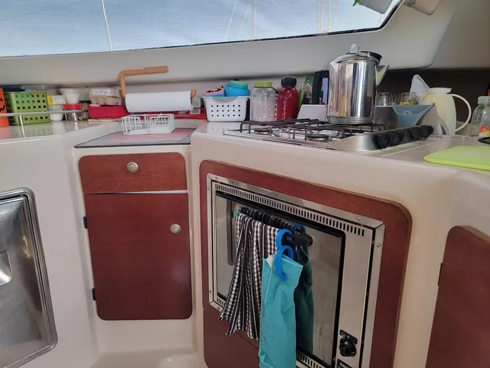 Cat Tales Yacht Photos Pics Compact kitchen area in a 1996 Fountaine Pajot Tobago 35 catamaran, featuring stove and storage.