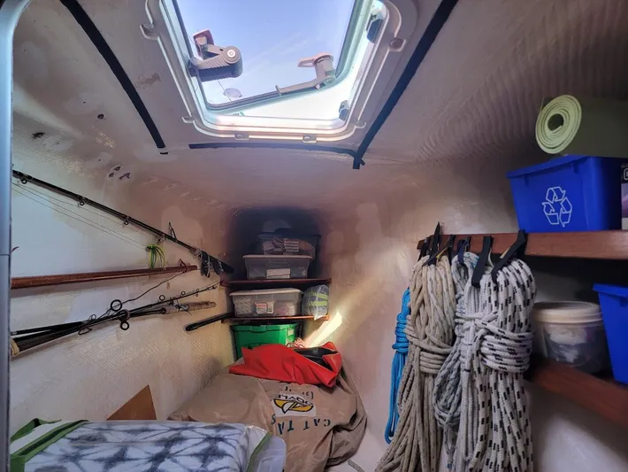 Cat Tales Yacht Photos Pics Storage area inside a 1996 Fountaine Pajot Tobago 35, featuring ropes, fishing rods, and bins.