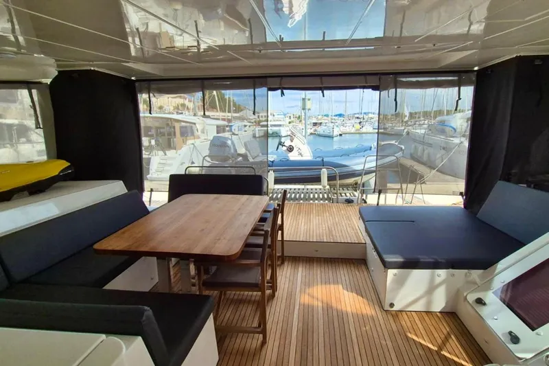 Tiga Yacht Photos Pics Interior of 2020 Lagoon 52 F yacht with seating and dining area, docked at marina.